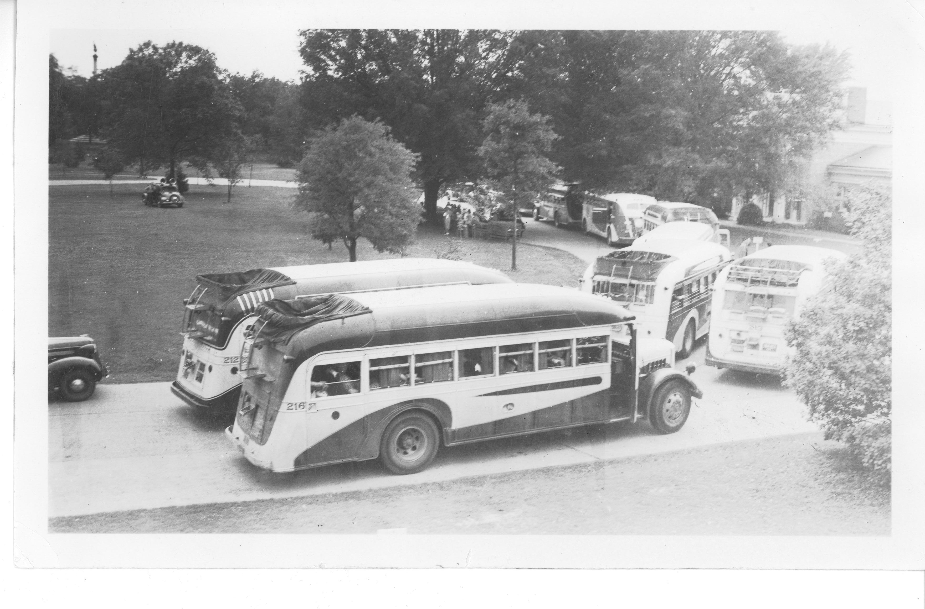 Black and white image of 1930s era buses parked outside the visitor center