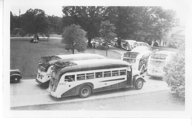 Historic black and white photo of buses parked in front of visitor center