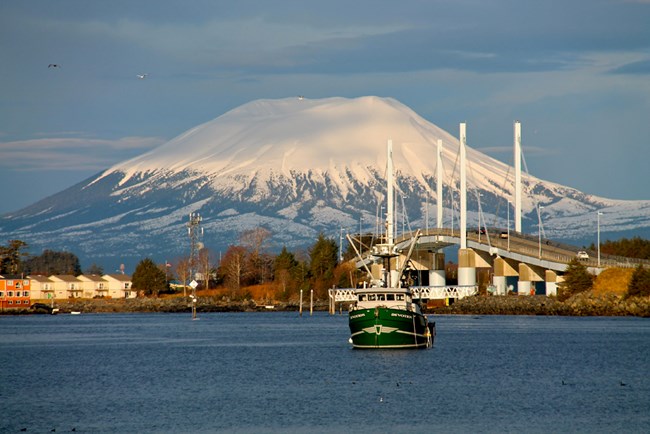 Fishing boat in water with bridge, town, and Mt. Edgecumbe in background