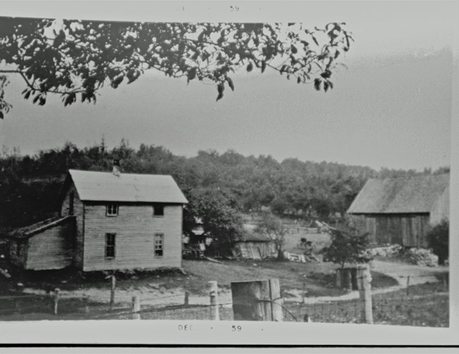 A quaint little farm sits on South Manitou Island, complete with a little farmhouse and barn. Trees surround the tranquil farm.