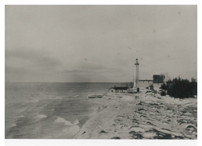 The South Manitou Island Lighthouse stands tall and proud on a snow-covered beach, shining its bright light out to guide wayward sailors to safety.