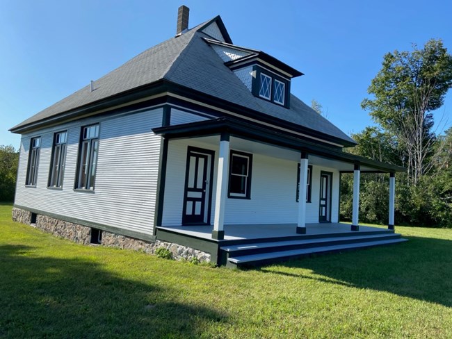 White school house with dormer and black trimmed windoew