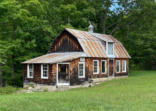 Cedar shake-sided, barn-shaped building with many white-framed windows