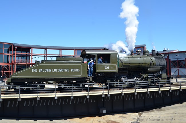 Dark green steam locomotive whistling off on turntable