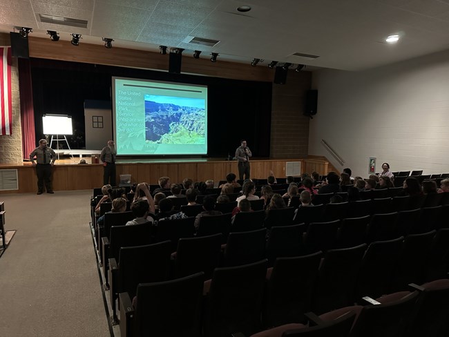 Three rangers speaking to students in an auditorium