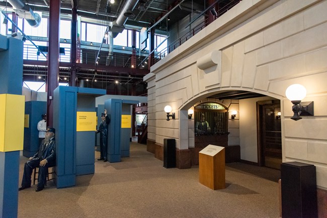 Interior of museum building featuring several mannequins and a faux station facade