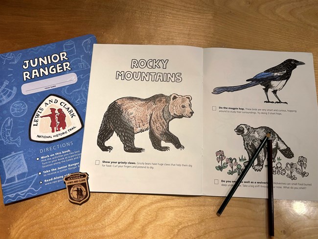 Close Lewis and Clark Junior Ranger booklet and coloring book on a desk with a badge.