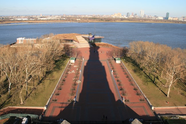 The statue of liberty's shadow over a brick walkway