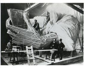 black and white photo showing Lady Liberty's hand under construction.