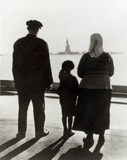 A newly arrived immigrant family on Ellis Island, gazing across the bay at the Statue of Liberty.