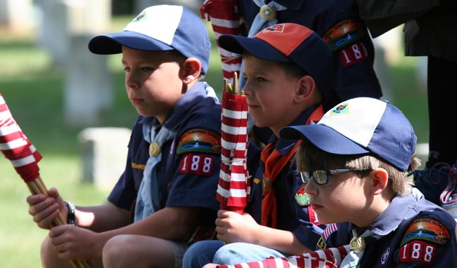 A group of Cub Scouts hold bundles of American Flags