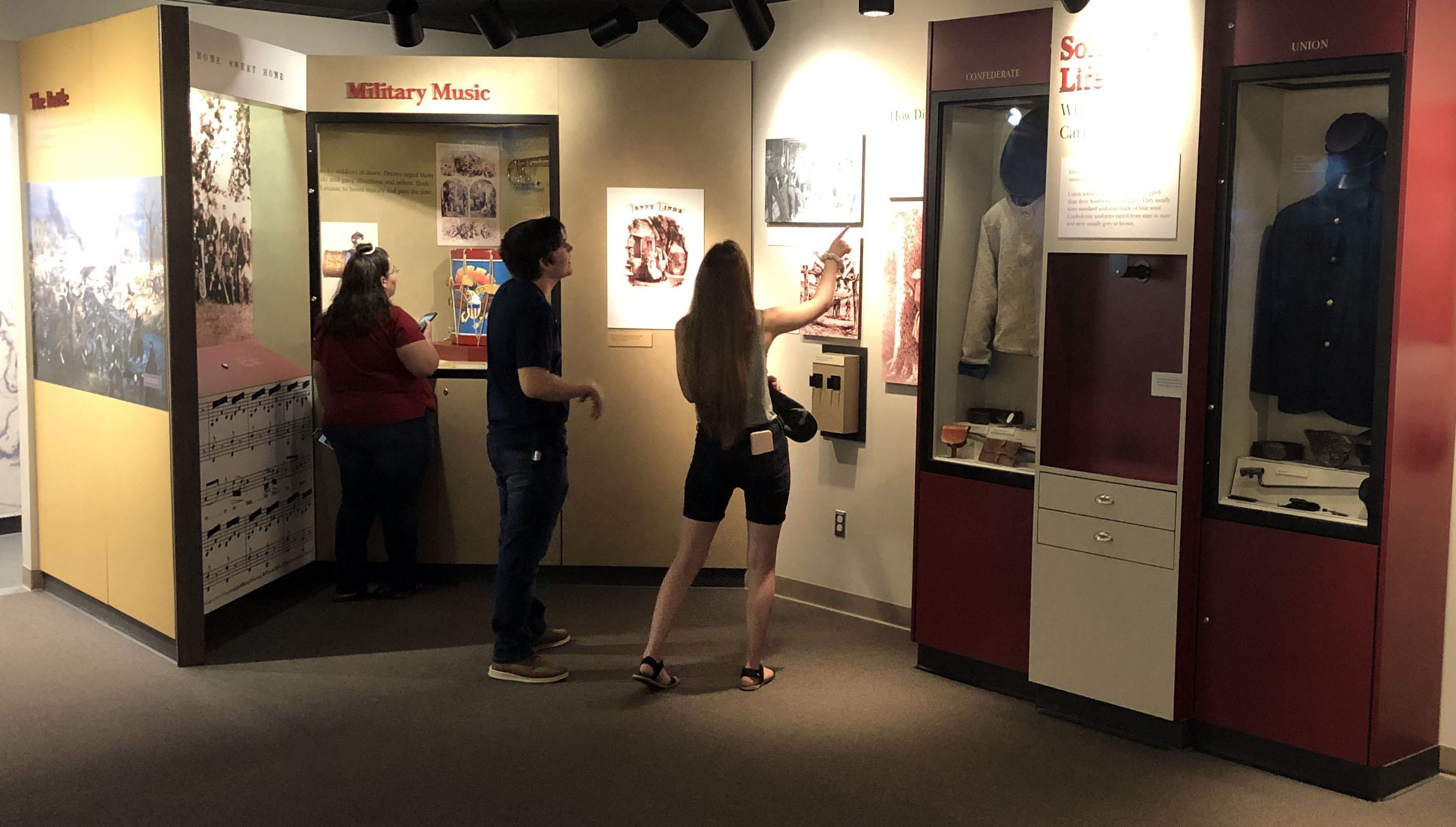 Two women and one man look at museum exhibits.