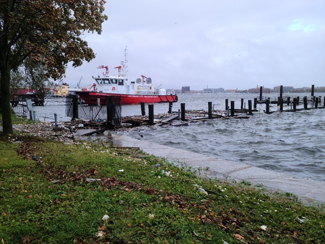 A storm surge event at Fort McHenry breaches the sea wall, damaging the dock and washing debris onto the lawn.