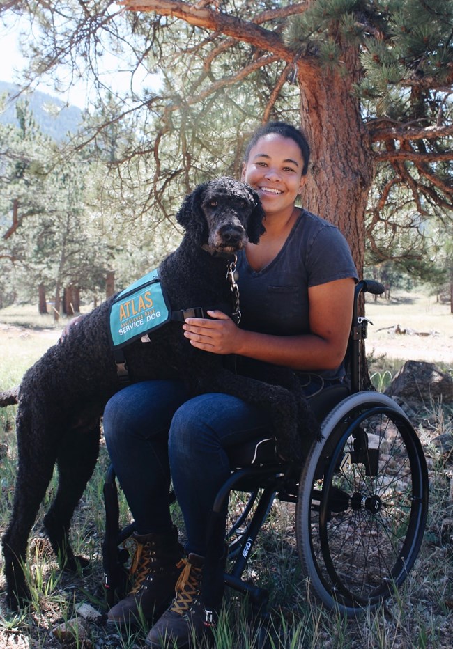 Woman in a wheelchair with her service dog in the woods