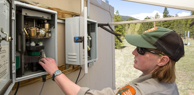 An NPS employee looking at outdoor air monitoring equipment