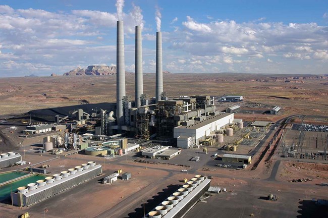 Photo of Navajo Generating Station, a large power plant with three towering smokestacks in the desert.