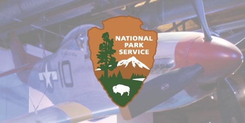 A NPS arrowhead in front of a photo of a plane with a red nose