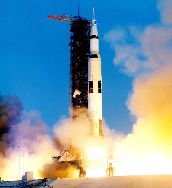 A large white rocket blasts off next to a tower