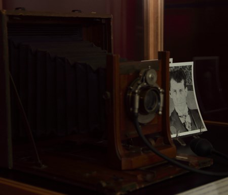 An old box camera in front of a picture of a man