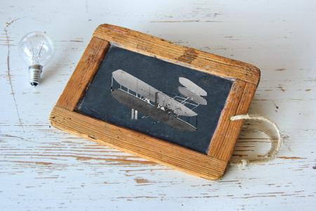 A chalk board with a plane drawing on it sitting next to a light bulb