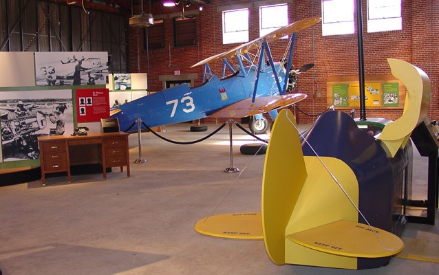 A blue airplane sits inside of a brick building