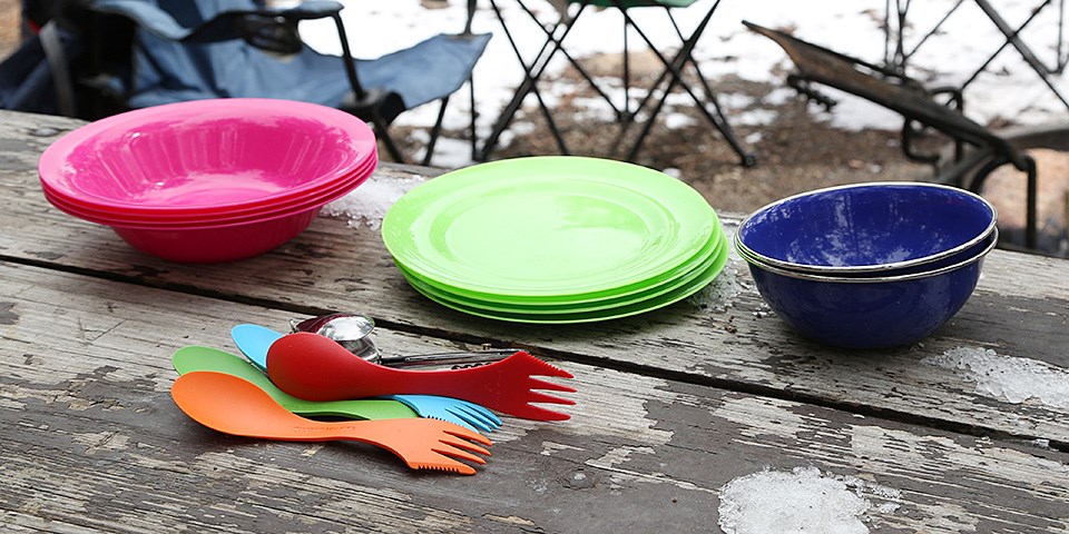 Colorful tableware and utensils on a picnic table