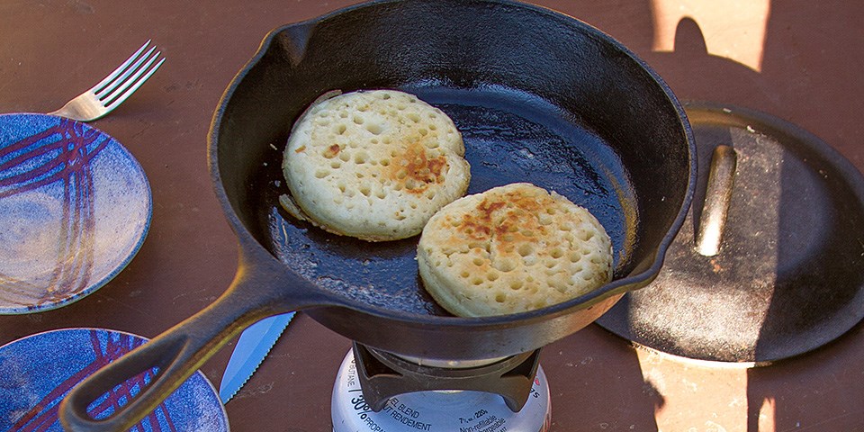 Crumpets cooking in a cast iron skillet