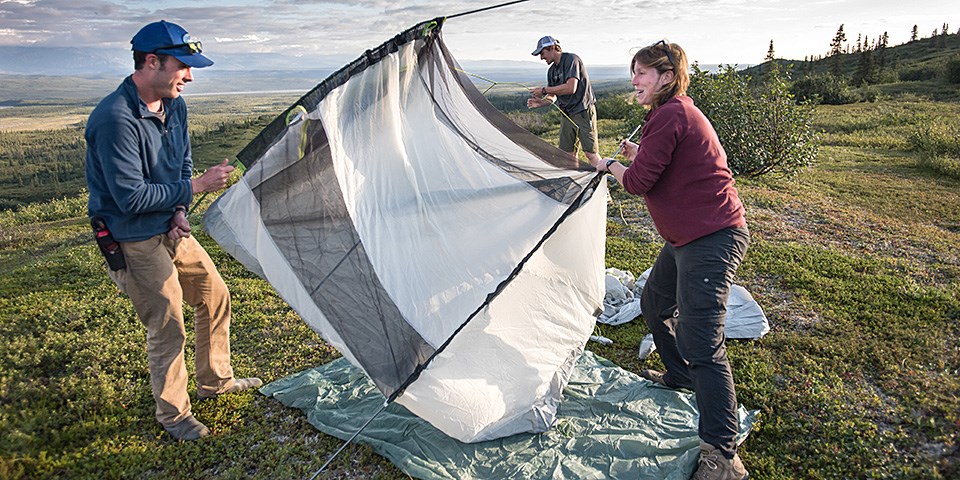 A man and a woman set up a white tent