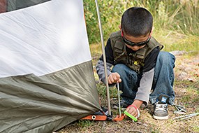 A child sets up a tent