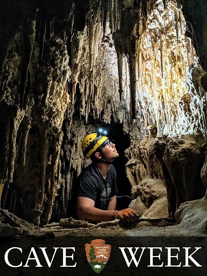 photo of a person inside a cave with large cave formations hanging down from above