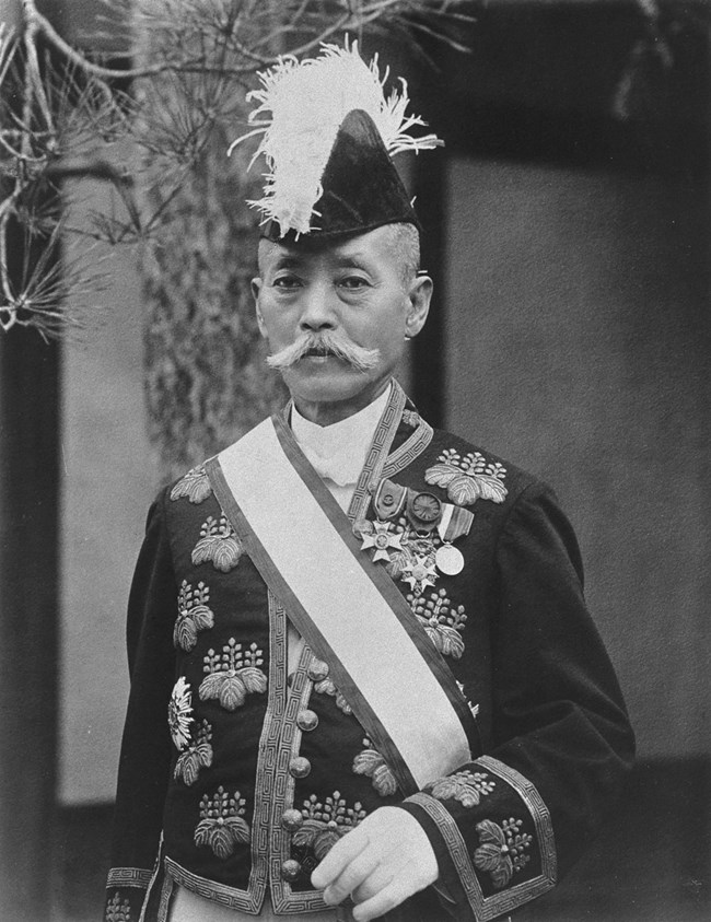 Black and white photo portrait of Mayor Yukio Ozaki in formal dress and a large ornate hat