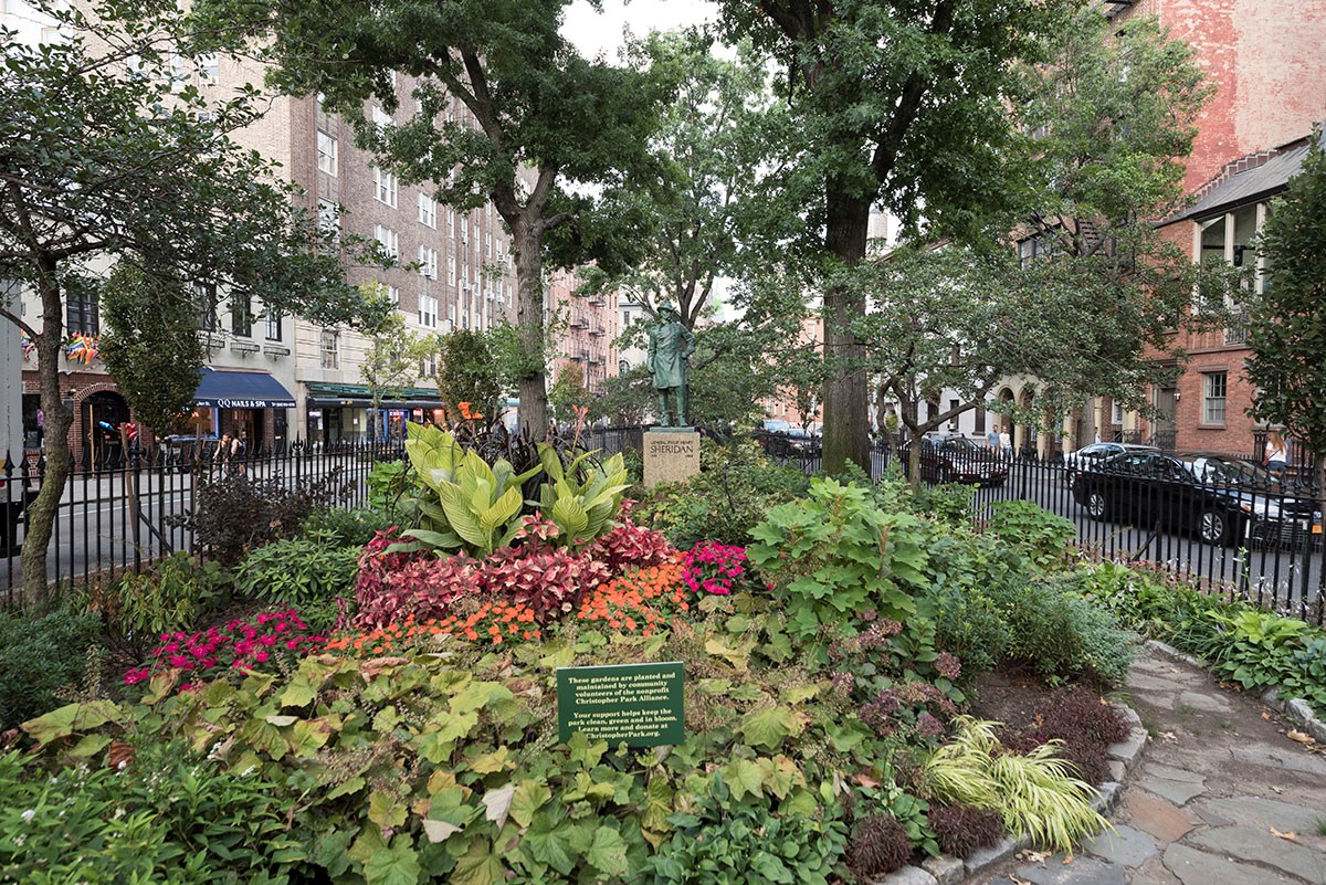 Wrought-iron fencing surrounds brick sidewalks and plantings of Christopher Park