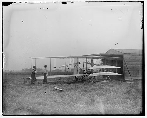 Wilbur and Orville Wright with their second powered machine beside a hangar in Huffman Prairie
