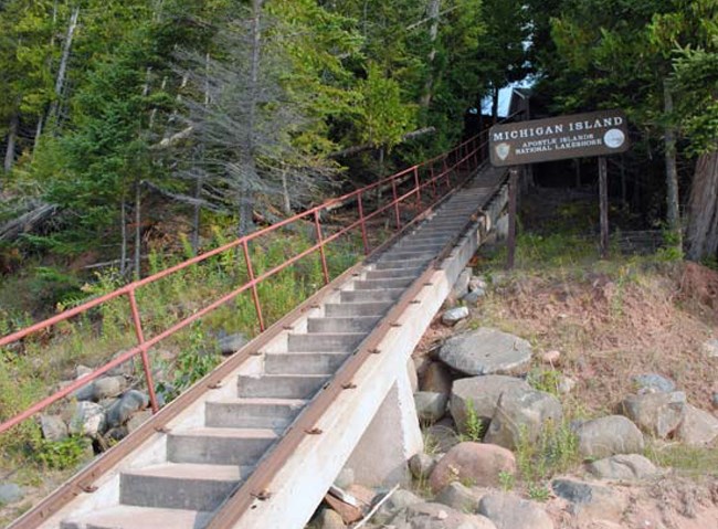 Tram tracks and a single railing on a steep staircase, where a sign says "Michigan Island"
