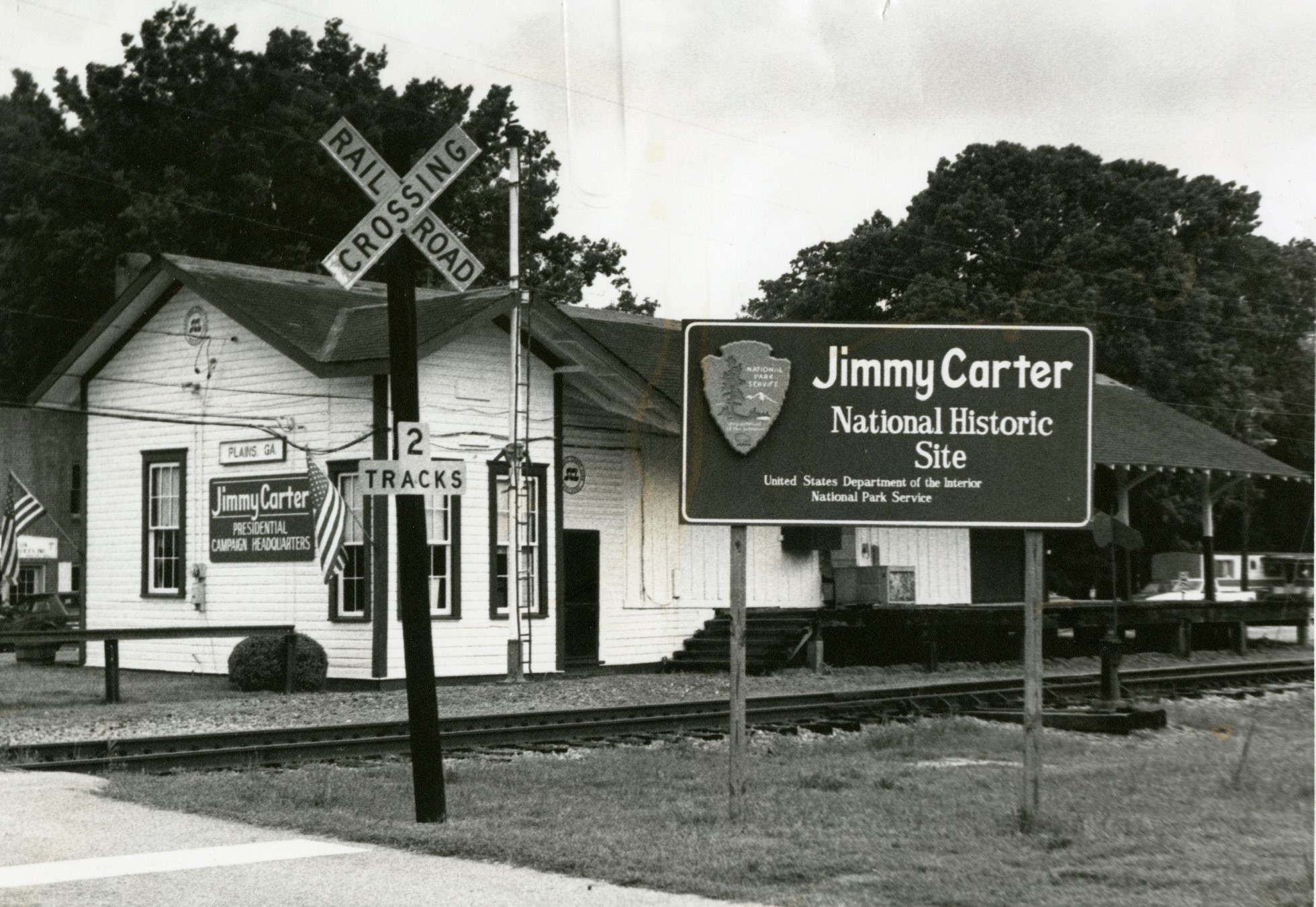 An NPS sign beside the one-story train depot and tracks says "Jimmy Carter National Historic Site"