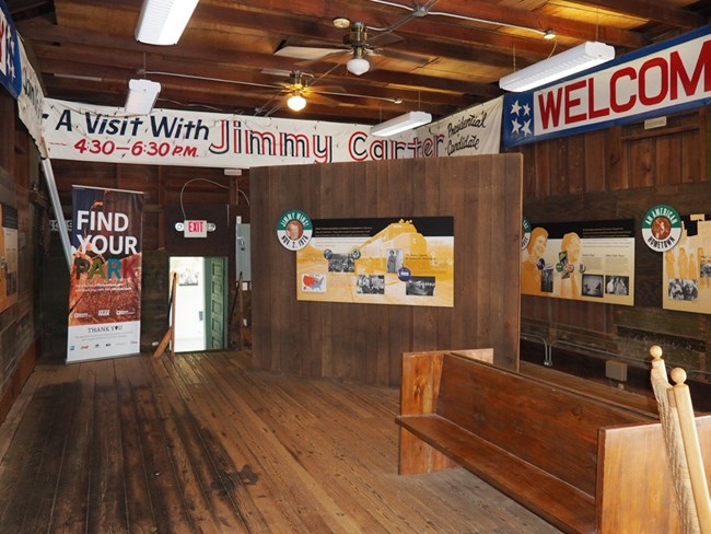 Wooden interior of the train depot has wooden benches and interpretive signs on the walls.