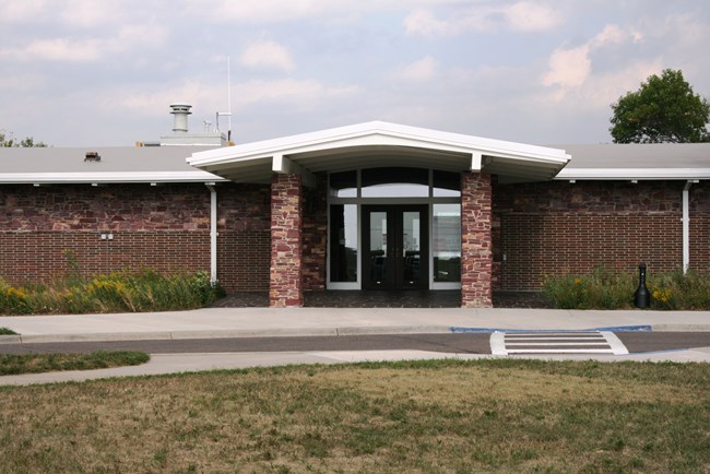 An overhang supported by brick columns covers the entrance to a long, single-story building