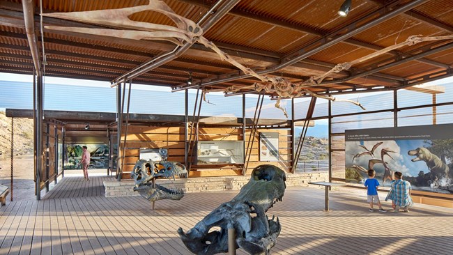 Photo of the inside of a fossil site visitor center with murals and castings of bones.