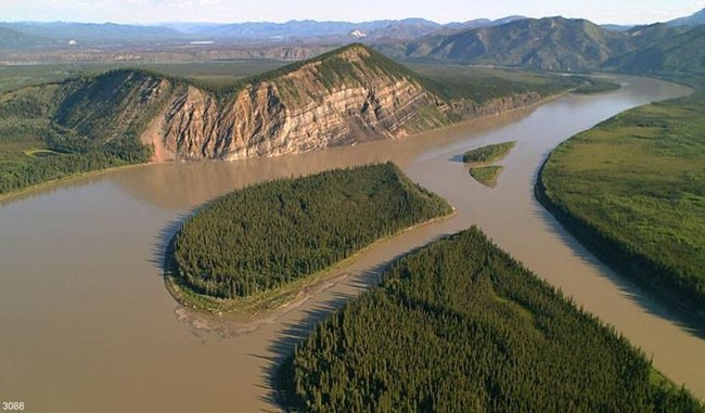 Aerial photo of a large muddy river and an eroded rocky bluff