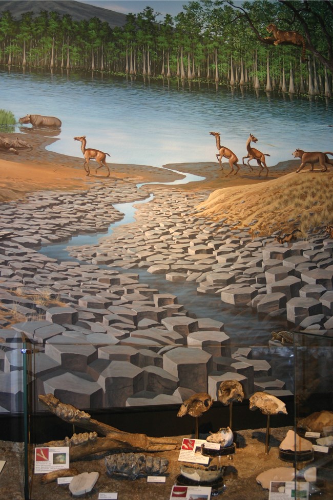 painted mural of prehistoric landscape with columnar basalt and animals