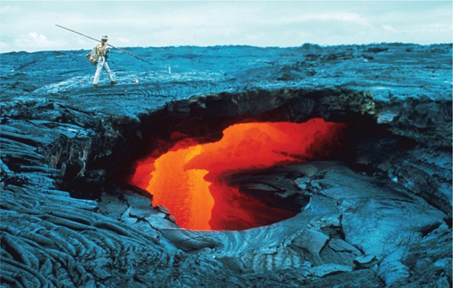 collapse hole in rock revealing flowing lava below the surface