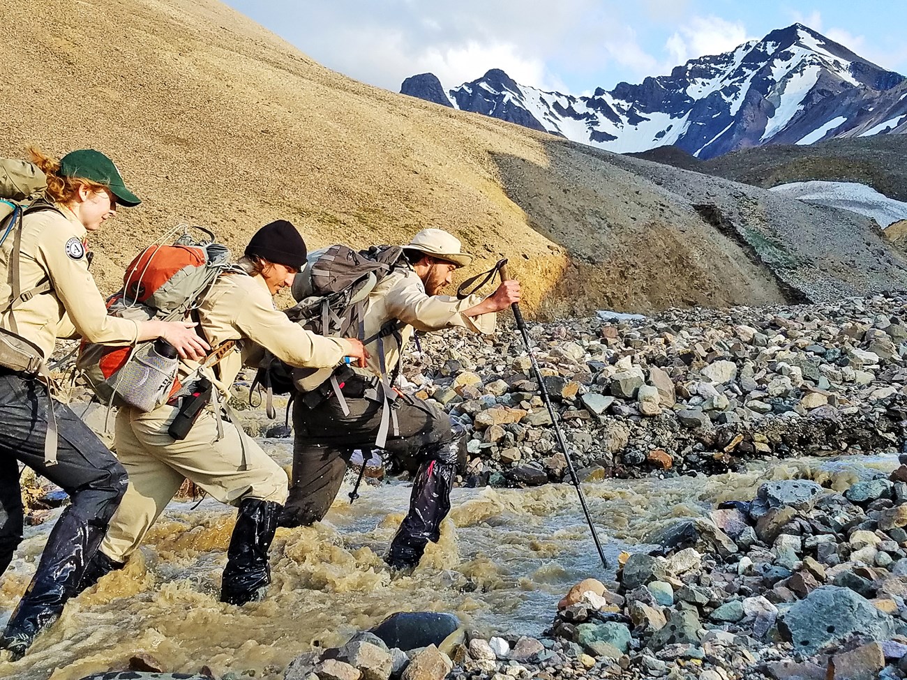 Three people charging across a mountain stream