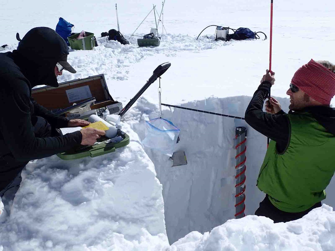 A researcher measures glacier characteristics.