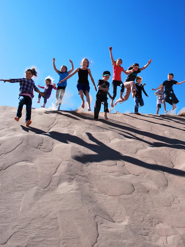 Teen kids jumping off sand dune