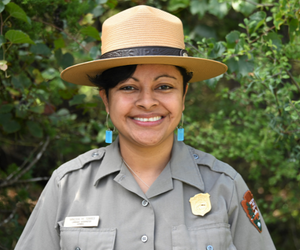 park ranger poses for picture in front of nature background