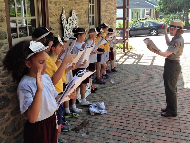 Park ranger swears in a group of Chesapeake Trail Junior Rangers at the Zimmerman Center for Heritage