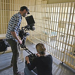 Two people film a jail cell