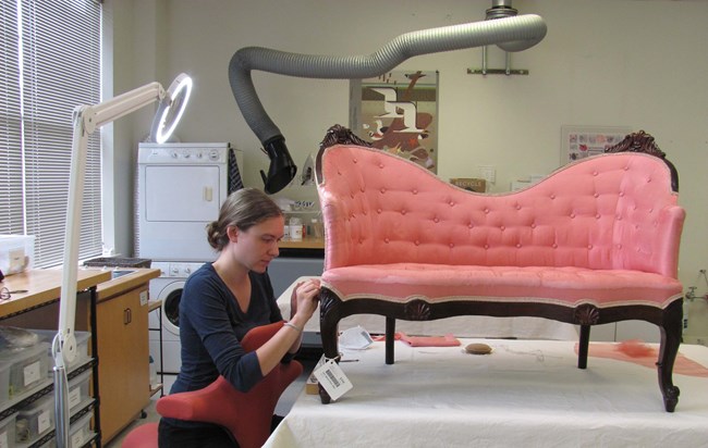 Woman upholstering a pink sofa