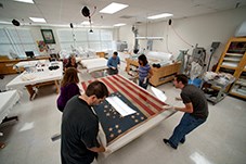 Six people hold an American flag from the Civil War.