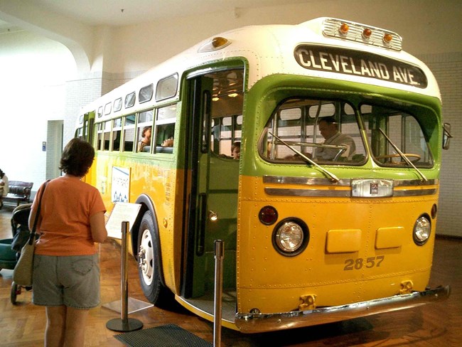 Indoor photograph of 1960s era public bus (green and yellow)
